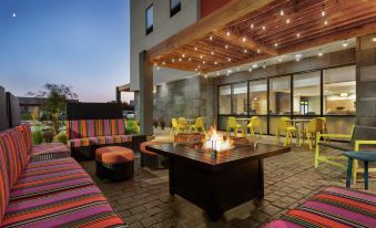 an outdoor patio area with multiple couches and chairs , creating a comfortable seating area for guests at Home2 Suites by Hilton Dekalb