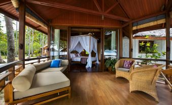 a luxurious wooden house with a large bed in the living room , surrounded by trees at Gangga Island Resort & Spa