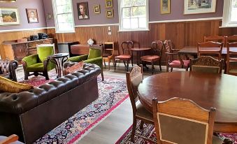 a room with wooden furniture , including couches and chairs , arranged around a table , creating a cozy and inviting atmosphere at Ratho Farm