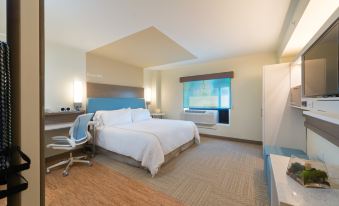 a modern hotel room with white bedding , a blue headboard , and two lamps on either side of the bed at Even Hotel Rockville - Washington, DC Area, an IHG Hotel
