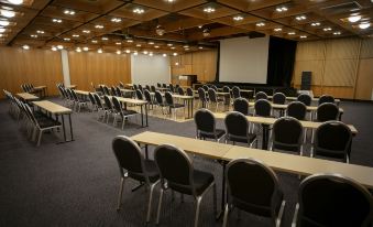 a large conference room with rows of chairs arranged in a semicircle , and a projector screen mounted on the wall at Hotel Selfoss