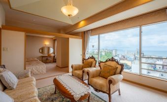a luxurious hotel room with a large window offering a view of the city , two armchairs , and a coffee table at Kaike Tsuruya