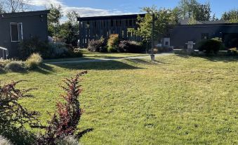 a large grassy yard with a house in the background and a flower garden in the foreground at Lodges on Vashon