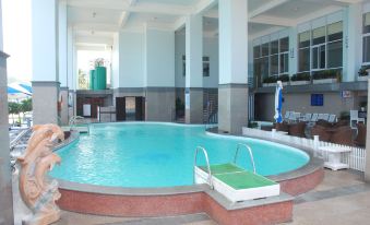 an indoor swimming pool with a large curved edge , surrounded by lounge chairs and umbrellas at Seagull Hotel