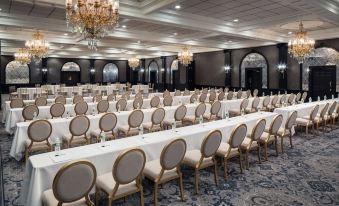 a large banquet hall filled with rows of tables and chairs , ready for an event at The Madison Hotel
