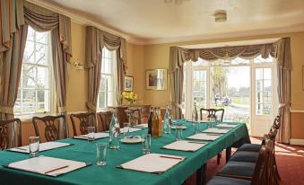 a dining room with a long table set for a meal , surrounded by chairs and equipped with wine glasses and other utensils at Corse Lawn House Hotel