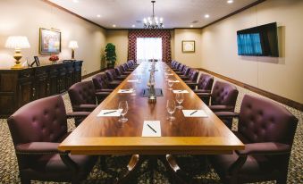 a long wooden table with chairs and wine glasses is set up in a conference room at Hotel Viata