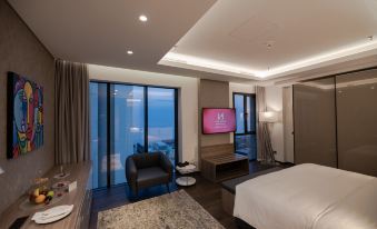 a modern hotel room with a large window offering a view of the ocean , a flat - screen tv on a stand , and a comfortable bed at Swiss-Belboutique Bneid Al Gar Kuwait