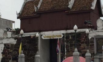 a traditional thai temple entrance with a sign in english and thai characters , under an overcast sky at Sakol Hotel