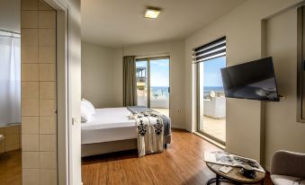 a hotel room with a king - sized bed and a large window overlooking the ocean , providing a scenic view at Marin Hotel