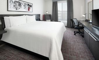 a large , white bed is in a hotel room with a window and desk area at Hilton Garden Inn Irvine Spectrum Lake Forest