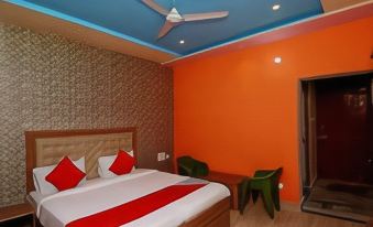a hotel room with a large bed , orange walls , and a green chair near the window at Collection O 27949 Hotel Kriti Green