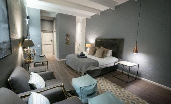 a modern living room with a gray brick wall , a large bed in the center of the room , and several chairs and ottomans at Ruby Rose