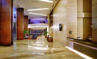a hotel lobby with marble floors , a large reception desk , and a television mounted on the wall at ASTON Pluit Hotel & Residence