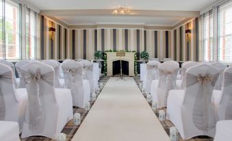 a long , narrow room with striped walls and white carpeting is set up for an event at Best Western Moore Place Hotel