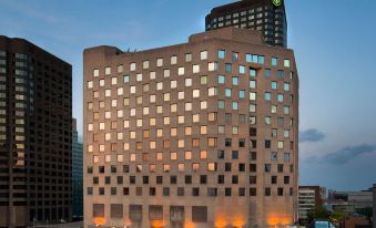 a large , modern building with multiple floors and balconies is lit up at night in a city at Doubletree by Hilton Montreal