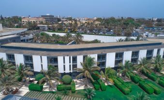 aerial view of a large building surrounded by palm trees , with a city in the background at Radisson Blu Hotel, Dakar Sea Plaza