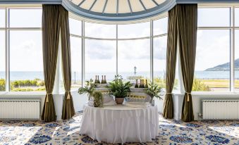 a table with a white tablecloth and various bottles of alcohol is set up in front of a large window at Slieve Donard