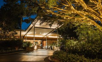 a nighttime view of a modern building with trees and lights , leading to an outdoor area at Crystalbrook Byron