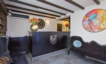a reception area with a black counter and a large clock on the wall , along with two chairs and a potted plant at Knights Inn