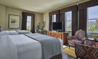 a large bed with a checkered blanket is in the middle of a room with a chair and window at Graduate Berkeley