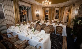 a large , well - decorated dining room with multiple tables and chairs set for a formal event at Overwater Hall