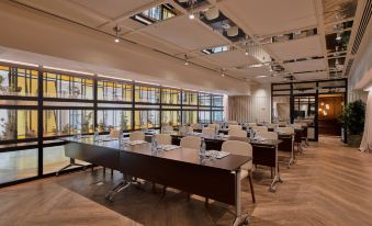 a conference room with multiple tables and chairs arranged in rows , facing large windows that offer views of the city at Only You Hotel Valencia