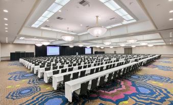 a large conference room with rows of tables and chairs , all facing the stage where two people are present at Wyndham San Diego Bayside