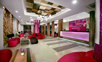a modern hotel lobby with red and pink furniture , a check - in desk , and a large checkered ceiling at favehotel Langko Mataram - Lombok