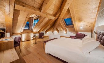 a large bed with white sheets is in a room with wooden walls and floors at Royal Hotel Cortina
