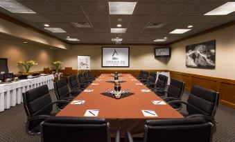 a conference room with a long table , chairs , and a projector screen displaying an award at Forest Park Hotel