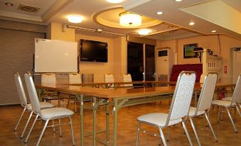 There is a conference room equipped with tables, chairs, and a large screen TV in the center at Hotel Tateshina