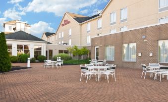 a large hotel with a patio area where several tables and chairs are set up for outdoor dining at Hilton Garden Inn Wooster