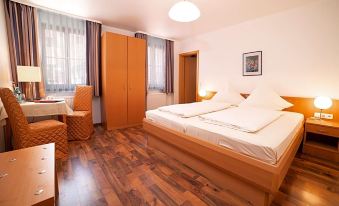 a hotel room with two beds , one on the left and one on the right side of the room at Akzent Hotel Schranne