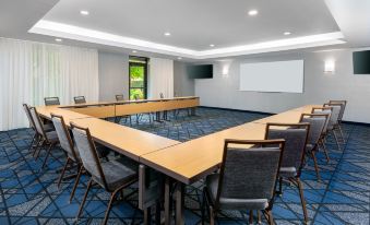 a conference room with a long table , chairs , and a screen on the wall , set up for a meeting at Courtyard Danbury