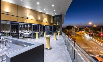 a modern restaurant with a large dining table and chairs , as well as a view of the city outside at Hotel Grand Chancellor Brisbane