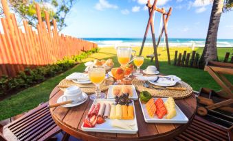 a table set with a variety of food and drinks , including fruits , bread , and beverages at Hotel Village Porto de Galinhas