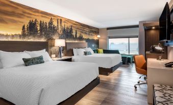 a modern hotel room with two beds , a desk , and a window , decorated with wood flooring and a large mural on the wall at Cambria Hotel Detroit-Shelby Township