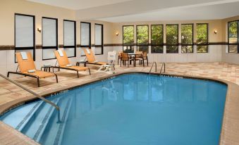 an indoor swimming pool with a lounge area and several chairs surrounding it , providing a relaxing atmosphere at Courtyard Lufkin