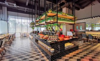 a modern kitchen with a black and white checkered floor , a dining area , and various food items on display at Grand Zuri Dumai