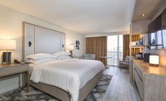 a modern hotel room with a large bed , white bedding , and a balcony offering views of the city at Sheraton Orlando North Hotel