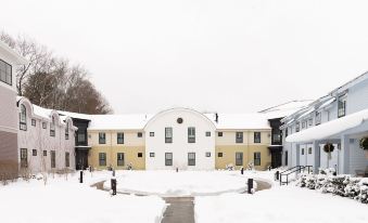 a snow - covered courtyard surrounded by multiple buildings , with the surrounding area covered in snow at Briar Barn Inn