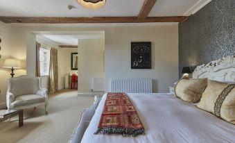 a spacious bedroom with a large bed , a fireplace , and a painting on the wall at Angel Hotel