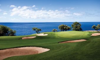 a beautiful golf course with a large body of water in the background , creating a serene and picturesque scene at Four Seasons Resort Lana'i