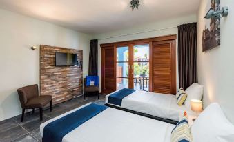 a modern hotel room with two beds , a tv , and a balcony door , all decorated in blue and white colors at Kunuku Resort All Inclusive Curacao, Trademark by Wyndham