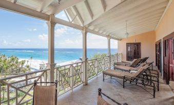 a covered balcony with multiple lounge chairs offering a view of the ocean , providing a comfortable outdoor seating area at The Crane Resort