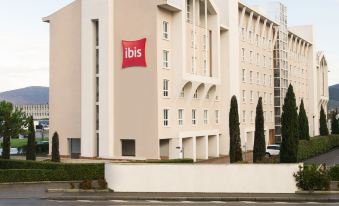 "a large white building with a red "" ibis "" logo on the side , situated on a city street" at Ibis Firenze Nord Aeroporto