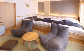 a modern bedroom with two grey bean bag chairs , a wooden table , and a bed with white bedding at Hotel Fuji