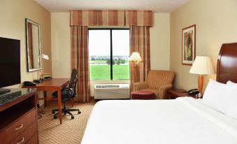 a hotel room with a large window , a bed , a desk , a chair , and a couch at Hilton Garden Inn Oconomowoc