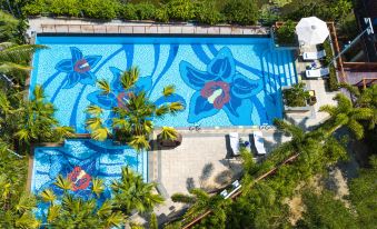 An aerial view reveals a swimming pool adorned with palm trees and other tropical decorations at Holiday Inn & Suites Sanya Yalong Bay